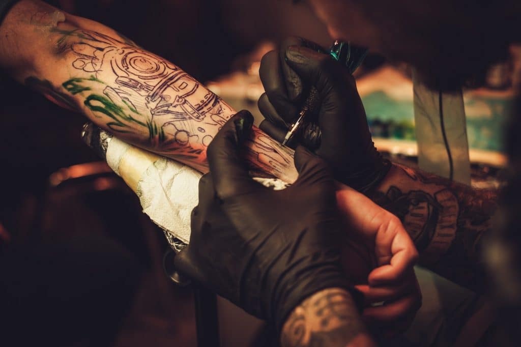 Tattoo artist makes a tattoo on a man's hand.